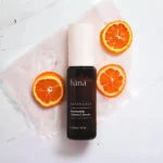 Close-up of Brightening Vitamin C Serum bottle next to oranges