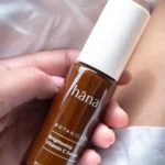 Close-up of a hand applying Brightening Vitamin C Serum, showing the texture of the serum on the skin.