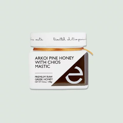 Front view of a jar of Arkoi Pine Honey with Chios Mastic, showcasing the vibrant label and rich, dark honey inside.