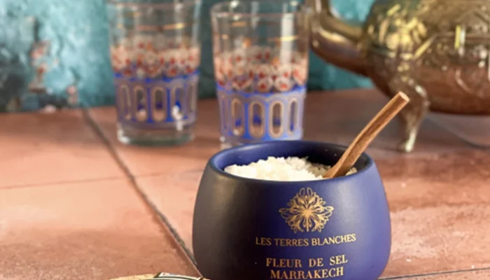 Close-up of white salt crystals in spoon above ceramic pot Close-up of white salt crystals in spoon above ceramic pot