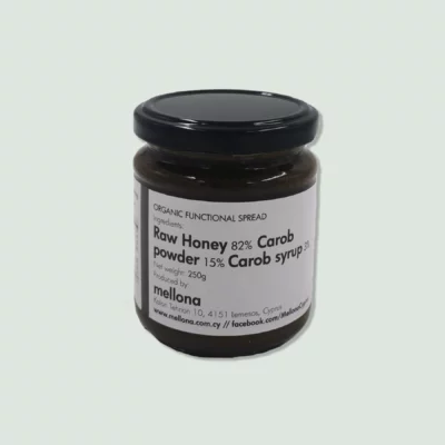 A jar of organic functional spread by Mellona, labeled as a blend of raw honey (82%), carob powder (15%), and carob syrup (3%). The jar has a black lid and a white label with black text detailing the ingredients and producer information.