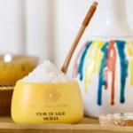 Close-up of bright white fleur de sel crystals in spoon above jar