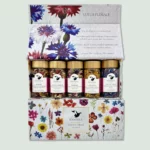 A box labeled "Lueur Florale" containing five jars of mixed herbs by Vanissa. The jars have golden lids and contain colorful blends of edible flowers and herbs. The box features a floral design with various flowers illustrated on it.