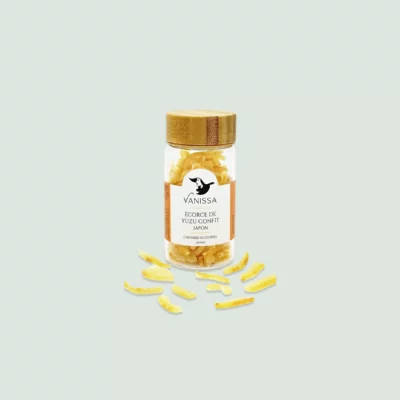 A glass bottle filled with vibrant candied yuzu peels, highlighting their bright yellow color and bumpy texture.