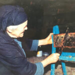 Grandmother extracting honey from honeycomb in Ikaria, Greece